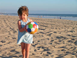 A toddler playing ball sports at the beach