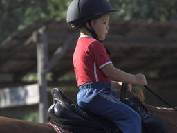 A kid learning how to ride a horse