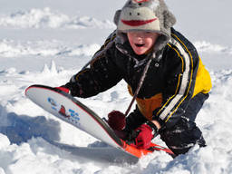 Sledding on the snow is very fun, as this excited boy shows.