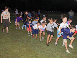 Cub scouts participate in various physical activities, such as a cooperation relay, to promote teamwork and self-reliance.