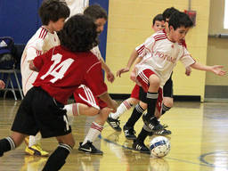 Young boys have a blast kicking the ball to score a goal in this game of futsal.
