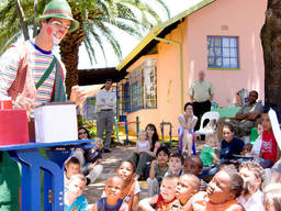 A clown magician performing his magic tricks in front of the captivated audience.