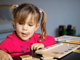 Cute little girl concentrates hard on her Marienkfer card game.