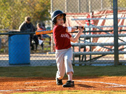 A young boy bats off the ball during a field match