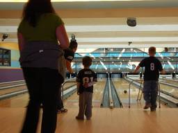 Kids playing ten pin bowling with their parents