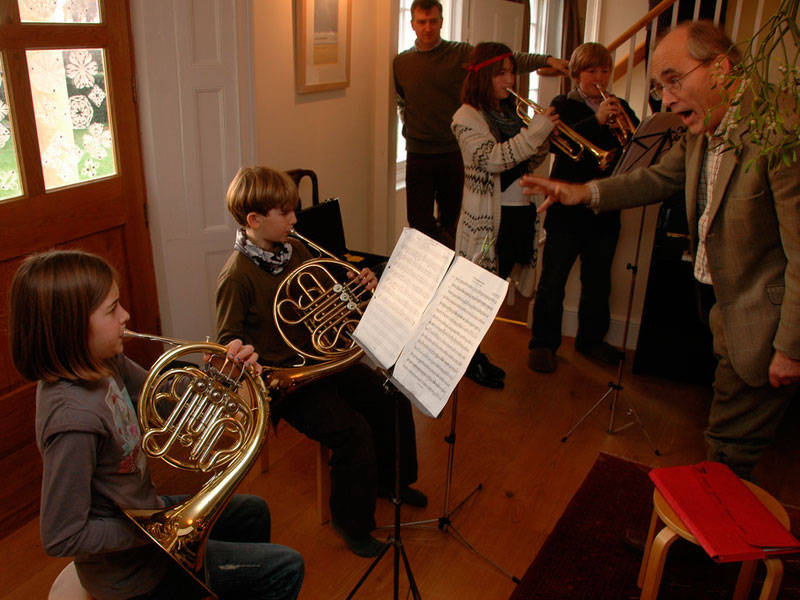 Children playing a piece from a score using a French horn