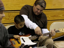 Young boy learning the basics of bass guitar playing