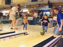 Toddlers with their fathers in the bowling alley.