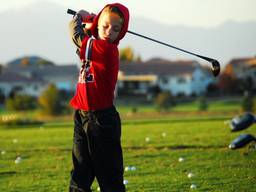 Young boy swinging his golf club.