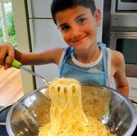 A kid learning how to cook pasta