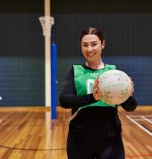 Woman holding netball in her hands on an indoor netball court