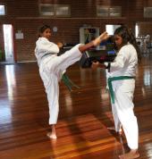 Young women practicing their karate kicks.