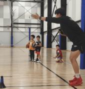 Coach guiding kids through shooting practice during basketball training for ages 4–8 in Melbourne.
