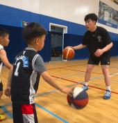 A group of children aged 4–6 dribbling basketballs during a weekend lesson at First Pick Basketball in Melbourne, smiling and learning coordination skills.