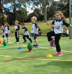 children having fun learning to kick a rugby ball